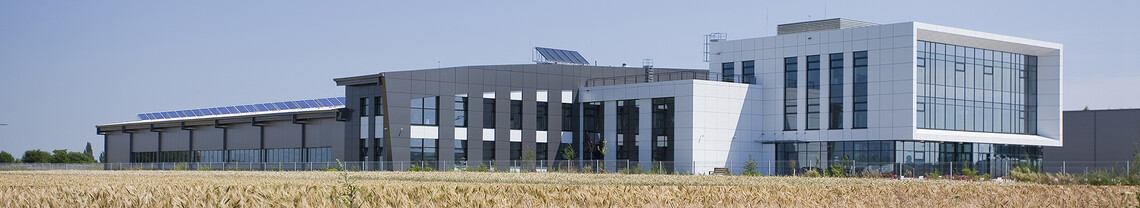 Duży budynek produkcyjny z panelami słonecznymi na dachu i częścią biurową